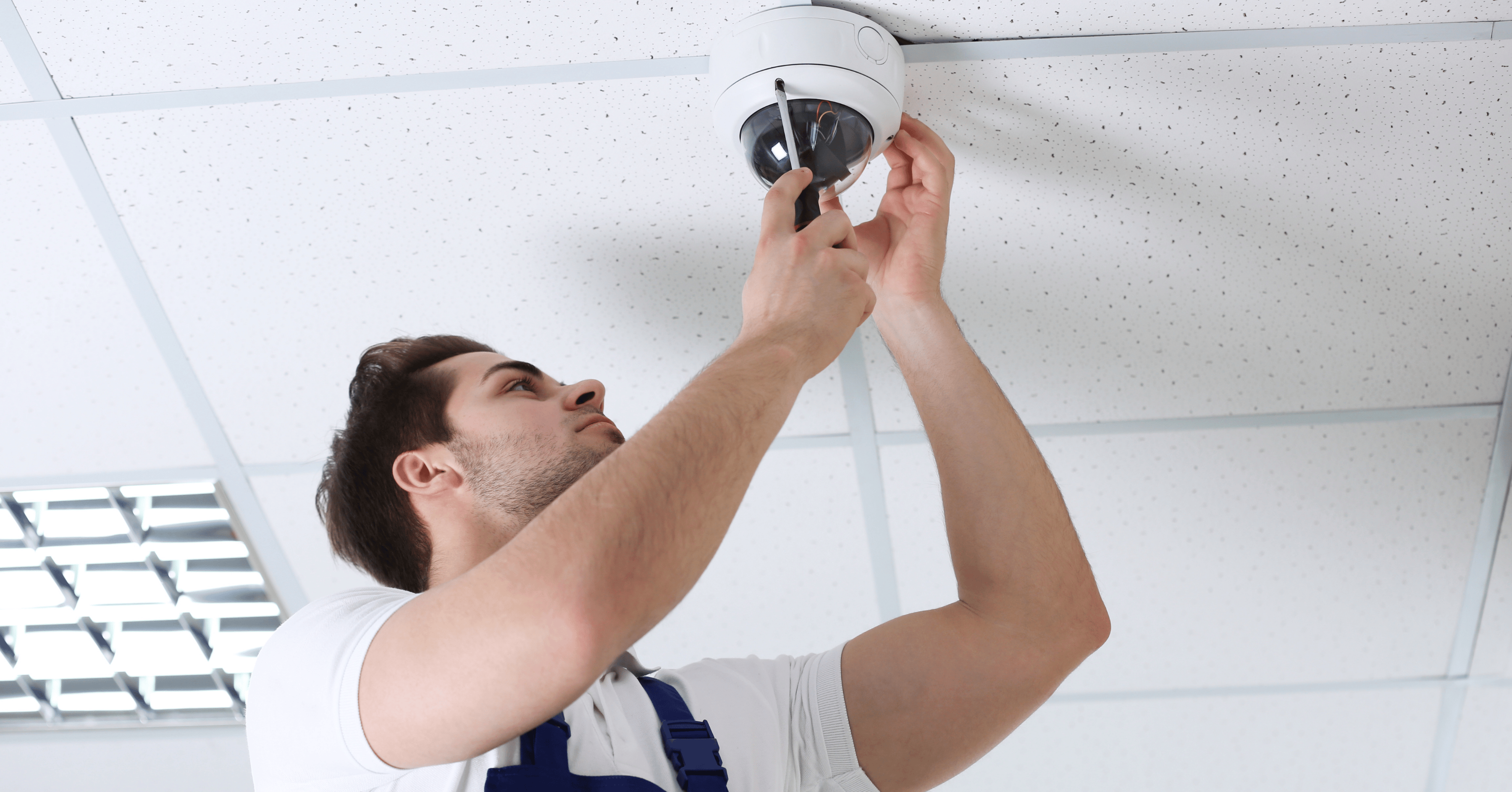 Monteur bei der Montage einer Dome Überwachungskamera an einer Decke im Innenbereich